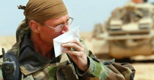 U.S. soldier in camouflage holding and kissing a handwritten letter with emotion, symbolizing connection and support from home.
