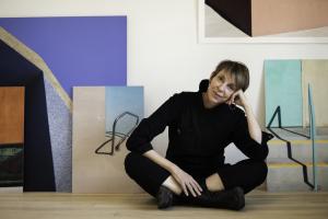 Photographer Natalie Christensen sitting on the floor of her Santa Fe, New Mexico studio with photographs surrounding her.