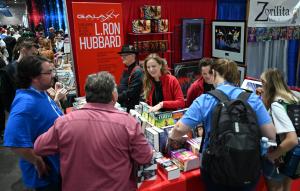 A continuous flow of customers at the Galaxy Press booth with three salespeople tending them at San Diego Comic Con 2025.