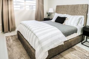 Cozy modern bedroom with woven bed frame, crisp striped bedding, and natural-toned decor featured in KTJ Krug LLC’s luxury rental collection.