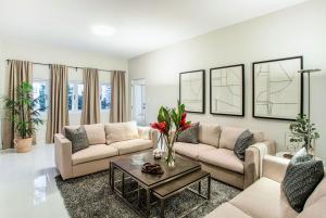Bright living room with neutral sofas, geometric wall art, and vibrant red floral centerpiece, part of KTJ Krug LLC’s San Juan property portfolio.