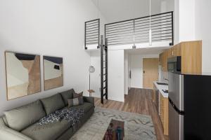 Loft apartment interior at Keystone Apartments with bonus area above living space, modern kitchen, staged living room furniture, and wood-grain flooring