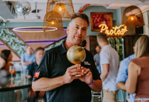 Kurt Yeghian holding a golden trophy labeled “Existing Conditions.”