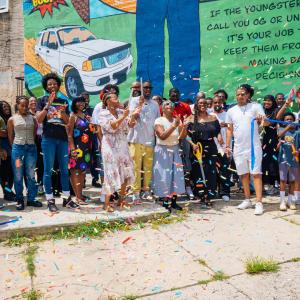 The completed Unk P mural by Nile Livingston stretches across the wall at 2600 Ridge Avenue showcasing bold comic-style art celebrating Paul Gripper’s life and impact