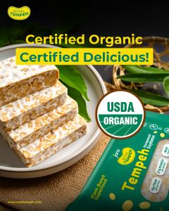 Stacked slices of Royal Tempeh USDA Organic fermented soybean tempeh on a plate with leaves, featuring “Certified Organic, Certified Delicious” text and packaging.