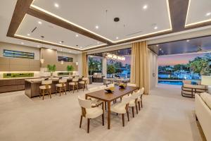 Luxurious open-concept kitchen with high ceilings, floor-to-ceiling glass, LED lighting, wood finishes, and expansive waterfront views.