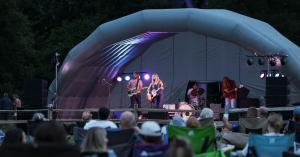 A concert stage with artists singing and a crowd enjoying the music.