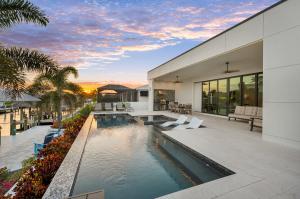 This modern waterfront Cape Coral home offers a resort-style pool, spa, outdoor kitchen, lounge seating, tropical landscaping and canal access.