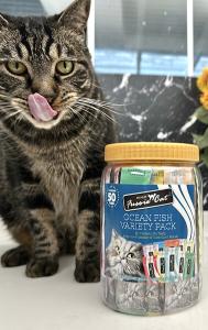 Cat enjoying Fussie Cat's new 50-count Variety Packs, licking face, cat puree treat