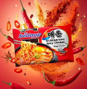 Mi Sedaap Korean Spicy Chicken Soup Ramen in red packaging, surrounded by chili peppers, spices, and seasoning explosion.