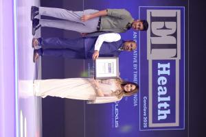 Three individuals on stage at the ET Health Conclave 2025 award ceremony, with one holding a framed award. The backdrop features the event logo, "ET Health" and "Conclave 2025," along with the Lexus sponsorship branding. The scene is illuminated with purp