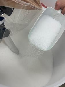 A scoop filled with polymers poured into a bin.
