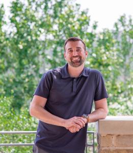 Torey Palmer, Chief Growth Officer at GBS standing outside, smiling and leaning against a railing in Austin, Texas
