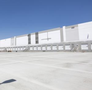 View of a long gray painted tilt-up wall with multiple dock doors.