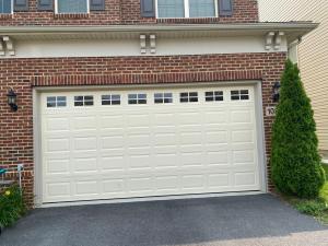 Carriage house style garage door with black decorative hardware installed in Potomac, MD.