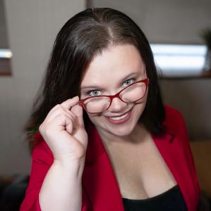Jen Perez smiling in a red blazer and red glasses, Texas-based profit strategist and founder of The Spicy CEO