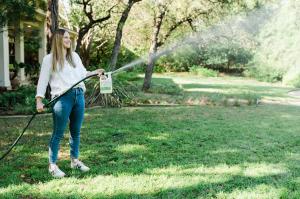 Woman sprays Wondercide Flea & Tick spray on yard for tick prevention.