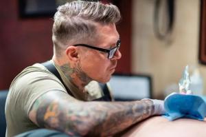 Tattoo artist Jason Elvis Martin tattooing a client in his private Nashville-area studio.