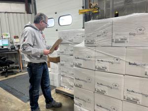 Bolt Printing employee checking labeled boxes of completed custom apparel orders ready for shipment.