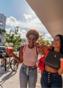 Two cheerful adolescent girls with backpacks representing Equilibrium Mental Health's target demographic for teen psychiatry services