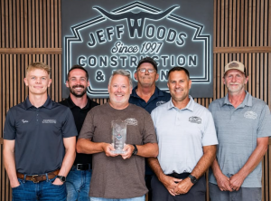 Jeff Woods Construction and Roofing Crew Poses with Award in Font of there logo.