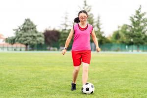 Girl with IDD playing soccer in a field