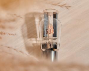 A single SELECT 5U4 vacuum tube against a light brown background.
