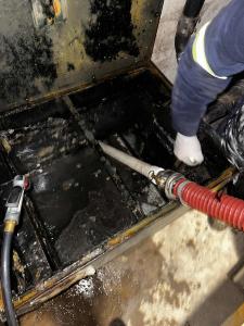 A envirogreen and filta kleen technician siphoning waste oil out a full grease trap for a busy restaurant in downtown brooklyn