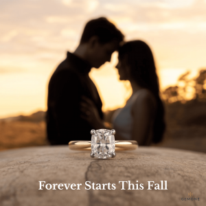 Close-up of a diamond engagement rings from Gemone Diamonds’ Fall Wedding Collection, with a couple embracing at sunset in the background.