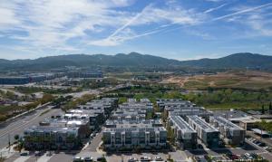 A far-away aerial photo of a large apartment complex that has a multi-family solar system on the rooftops.