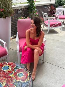 Lisa Stewart Sitting in a Pink Dress on a patio; Photo Credit: Lisa Stewart