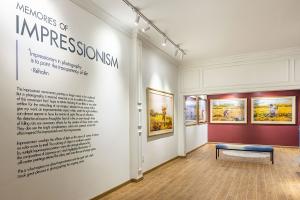 Wide-angle shot of the Impressionism-themed gallery room featuring wall text explaining Réhahn’s creative approach, with large framed photographs.
