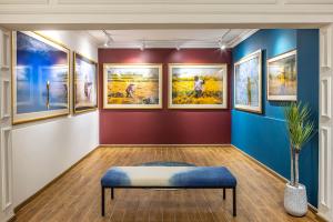 Interior view of the Réhahn Gallery in Vietnam, showing framed photographs on deep red and blue gallery walls with a central seating bench.