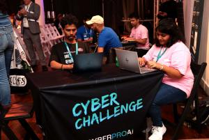 Two students sitting on a table with laptops engaged in a CTF event in a hall of a cyber conference in NYC
