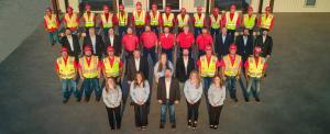 Group photo of Schulte Roofing team in safety vests, hard hats, and business attire standing together outside headquarters.