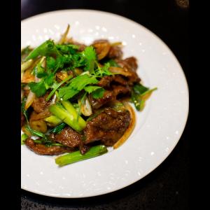 a vivid photo of the beef and green onion stir fry dish as shangHai taste