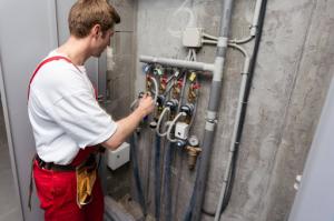 Plumber tightening a residential water meter connection using an adjustable wrench.