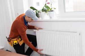 An HVAC technician fitting a radiator to optimize energy savings during professional heating services.