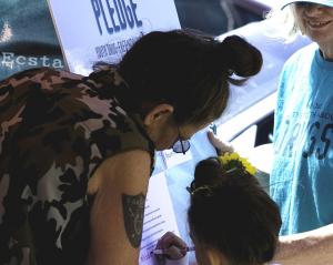 Grandmother helps her granddaughter sign the Drug‑Free World pledge.