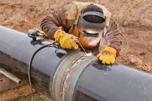 Man in welding suit welding pipeline