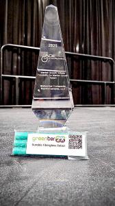 Three small bars of Greenbar2X fiberglass rebar in a labeled plastic bag with a title and QR code in front of a trophy.