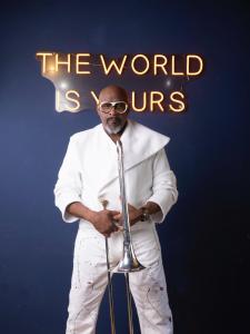 Musician Jeff "Mr. Trombone" Bradshaw in ultra modern white suit holding his trombone vertically