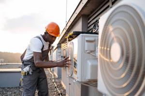 HVAC technician installing an outdoor cooling system using a tablet to guide setup and diagnostics.
