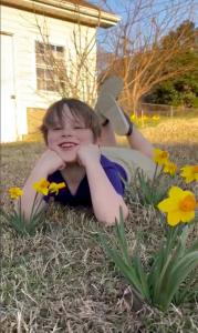 American Meadows Customer Photo. Young boy smiling beside blooming daffodils in spring, planted the previous fall. The image highlights how fall bulb planting is simple and enjoyable for gardeners of all ages, making it a fun family activity.