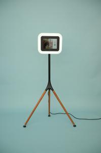Voast Booth on a Blue Background. Three wooden legs support a sleek and modern screen with a built-in ring light.