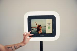 Hand adjusting the ring lighting on a Video Booth with the text "Raise a Toast" on the screen.