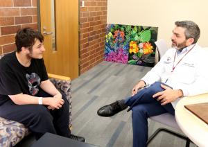 Shriners Children's Pediatric Psychologist and Researcher Kyle Deane, Ph.D., speaks with patient Jeremy.