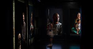 Dark walls display floor to ceiling black and white photographs of people living with Usher syndrome