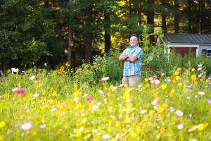 Wildflower expert Mike Lizotte standing in a colorful mini meadow in full bloom, showcasing the results of his trusted gardening methods and deep knowledge of meadow cultivation.