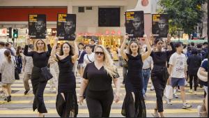 Heather Richmond and four Bitcoin Boxing Ring Girls holding “Culture Hits Harder” posters while walking through a crowded Hong Kong crosswalk.